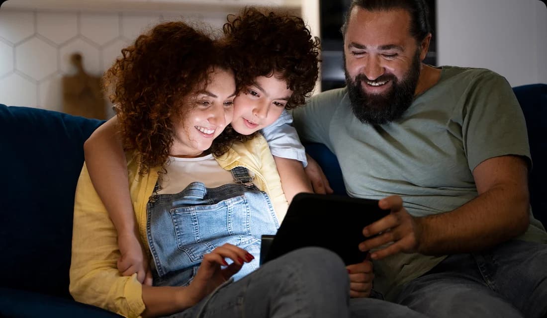 Family sitting on couch looking at tablet together